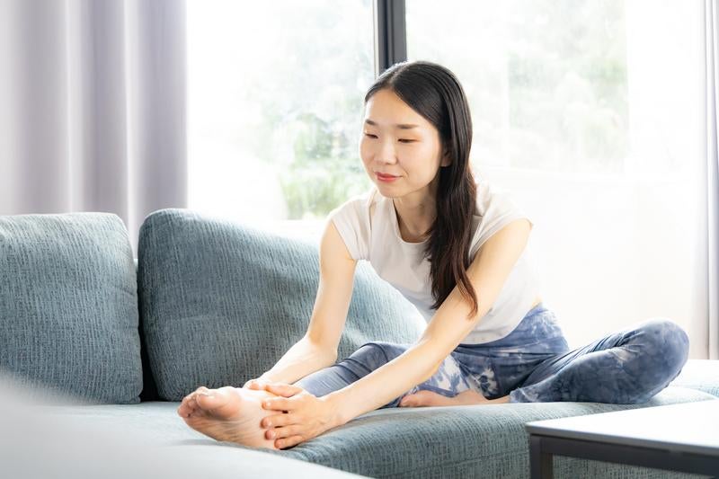 ソファに座って微笑む白いTシャツの女性の写真