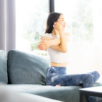 自宅のソファでストレッチ運動をする女性の写真