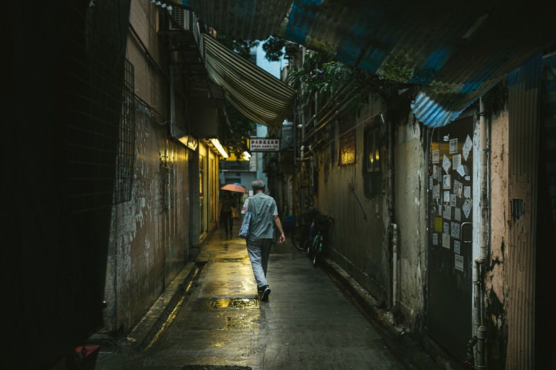 小雨が降る下町の路地裏と歩行者（香港）の写真