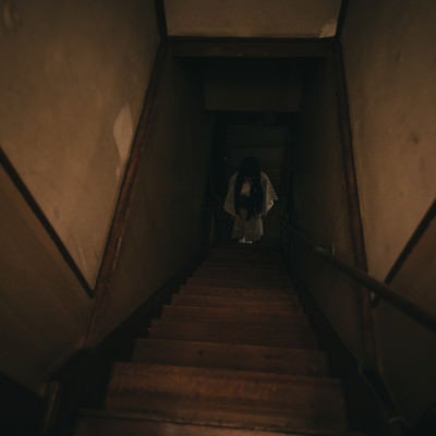 古民家の階段下に立つ女性の姿の写真