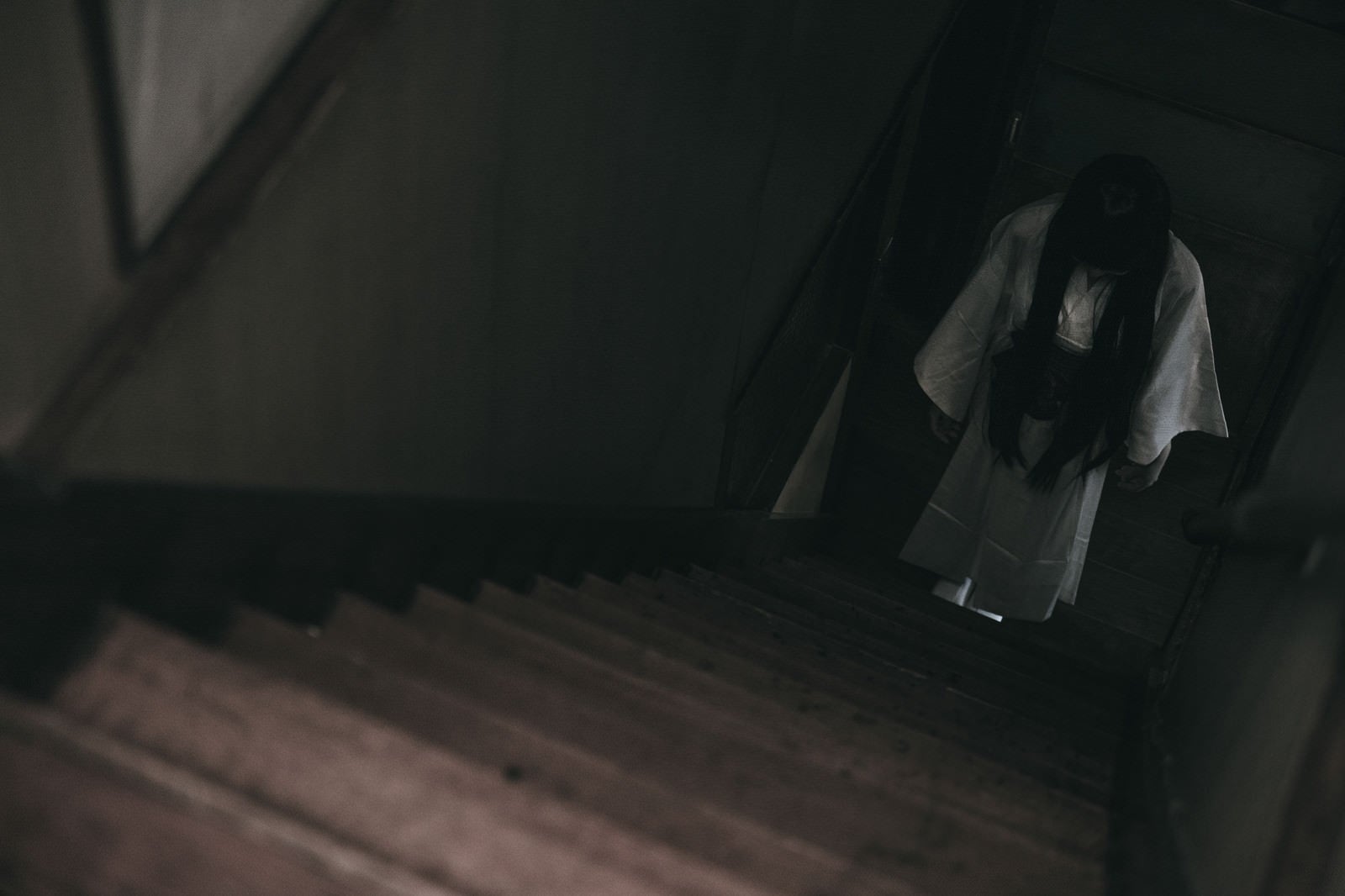 「暗い階段下に白装束の女性がうつむき竚む」の写真［モデル：緋真煉］