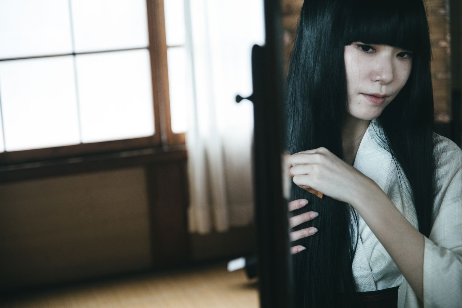 「黒髪の日本人女性が櫛で髪をとく様子」の写真［モデル：緋真煉］