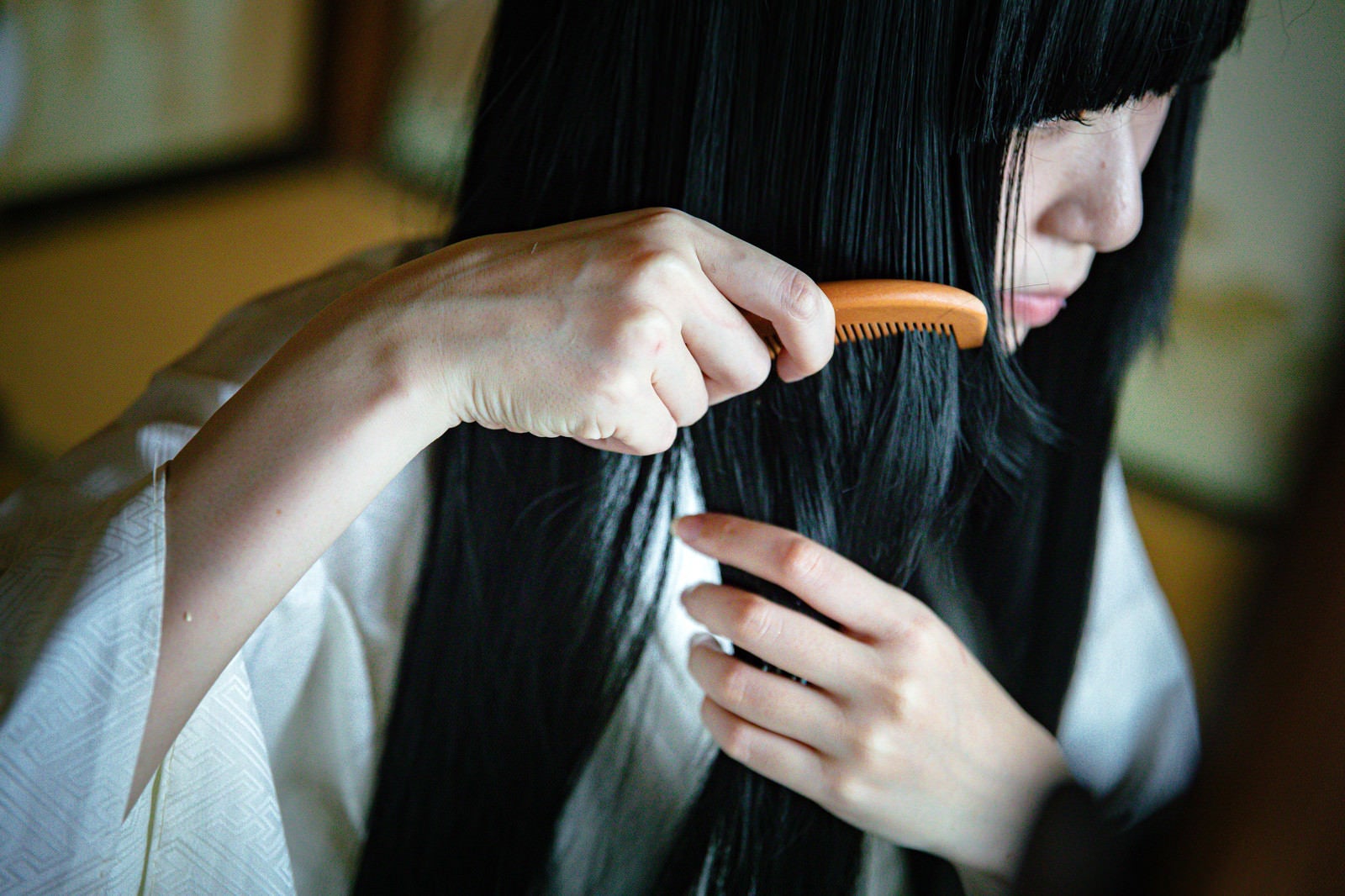 「長い黒髪にくしをとおす女性」の写真［モデル：緋真煉］