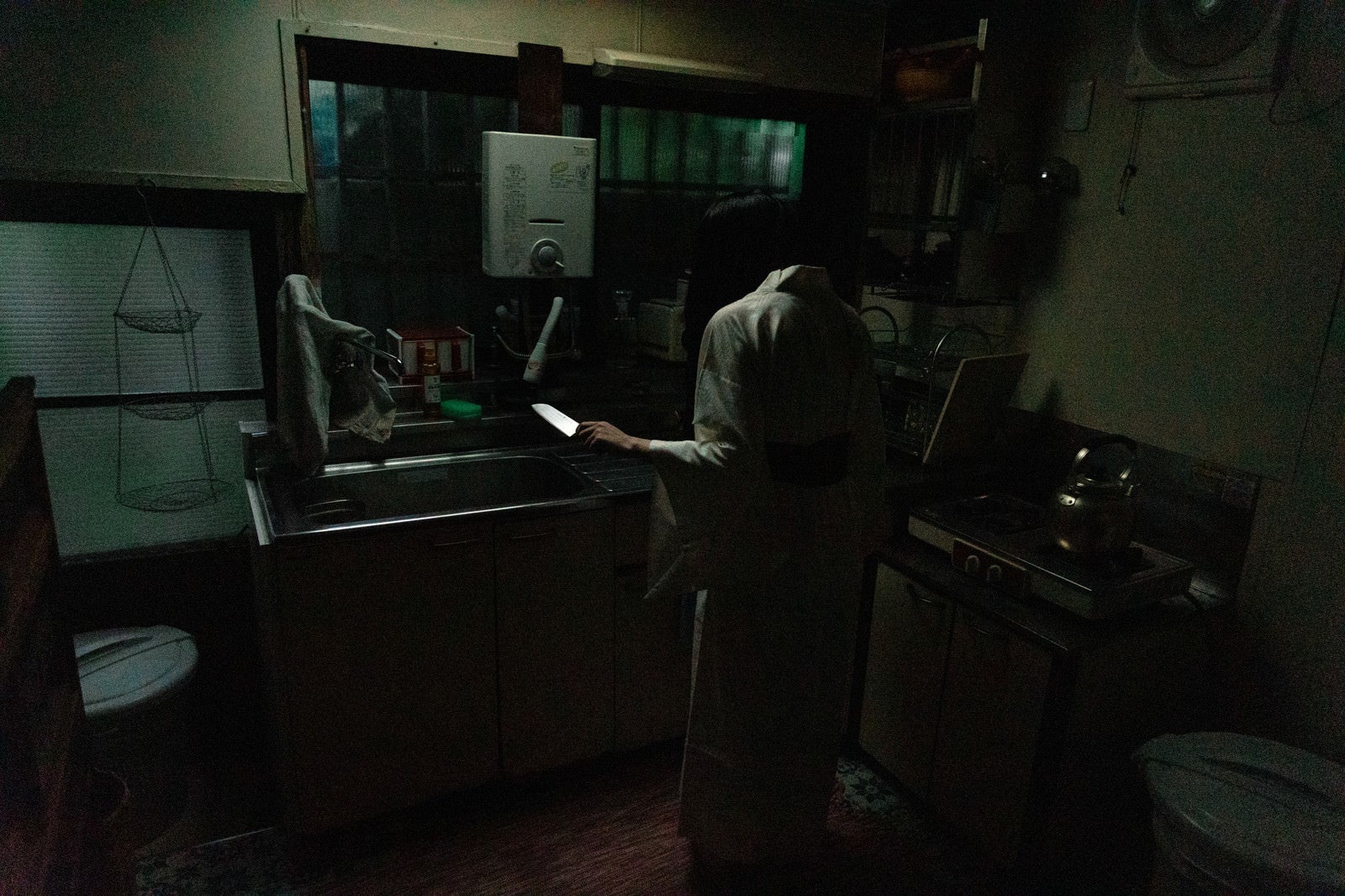 「包丁を片手に立ちすくむキッチンの幽霊」の写真［モデル：緋真煉］