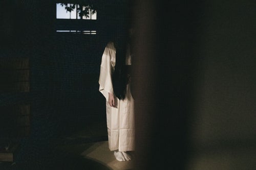 暗い和室に白装束の女性…の写真