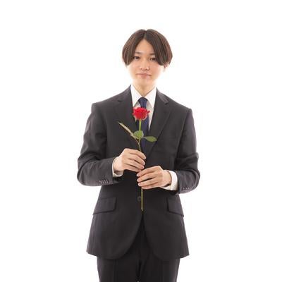 赤い薔薇を持って意中の人に告白する男性のポートレートの写真