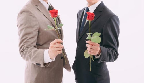 薔薇の花を持って告白する男性二名の写真