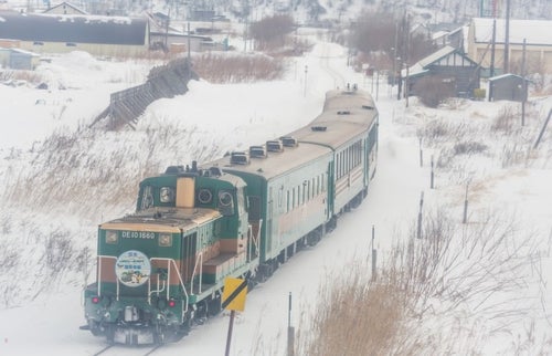 雪の中を走る運輸車両の写真