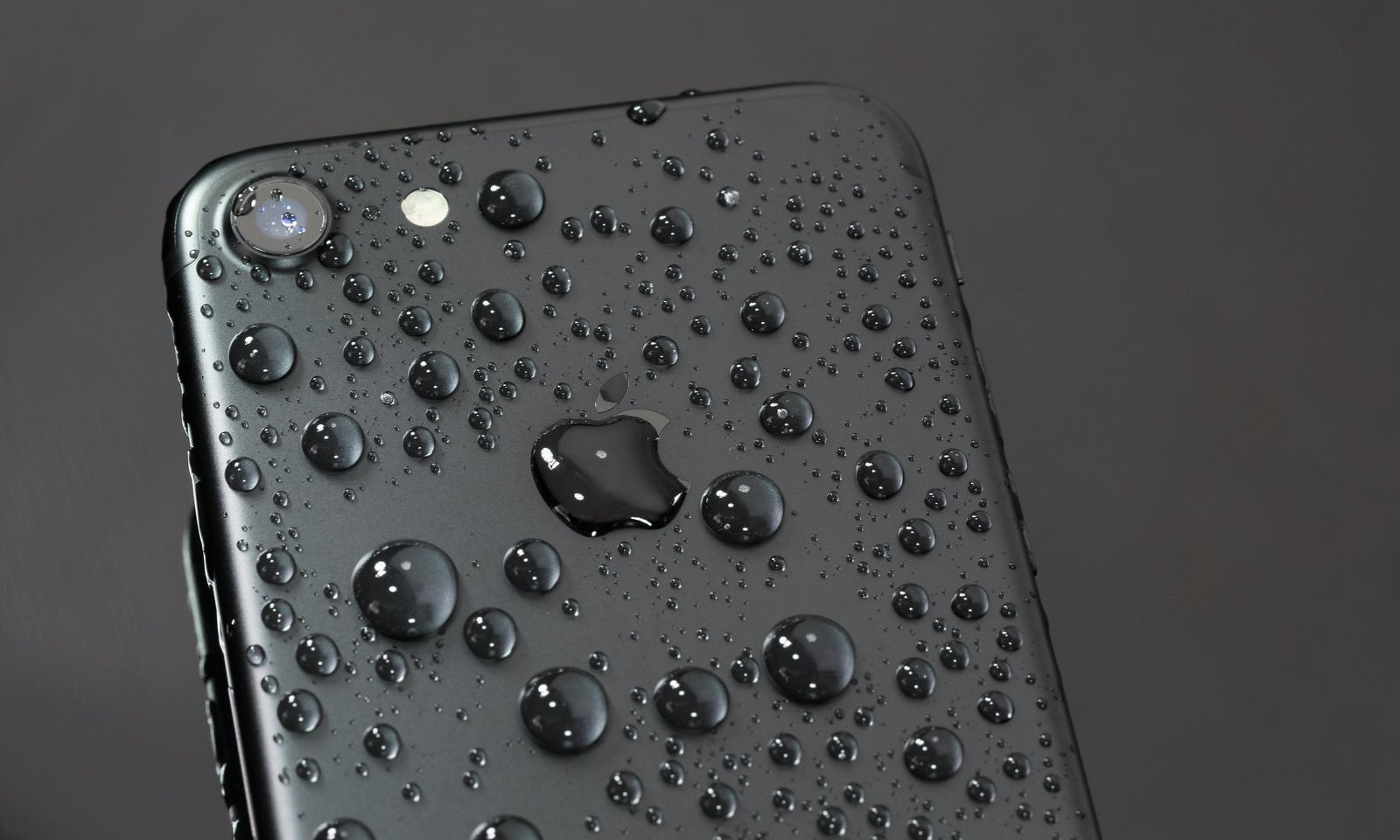 「水に濡れても美しいブラック色のスマートフォン | フリー素材のぱくたそ」の写真