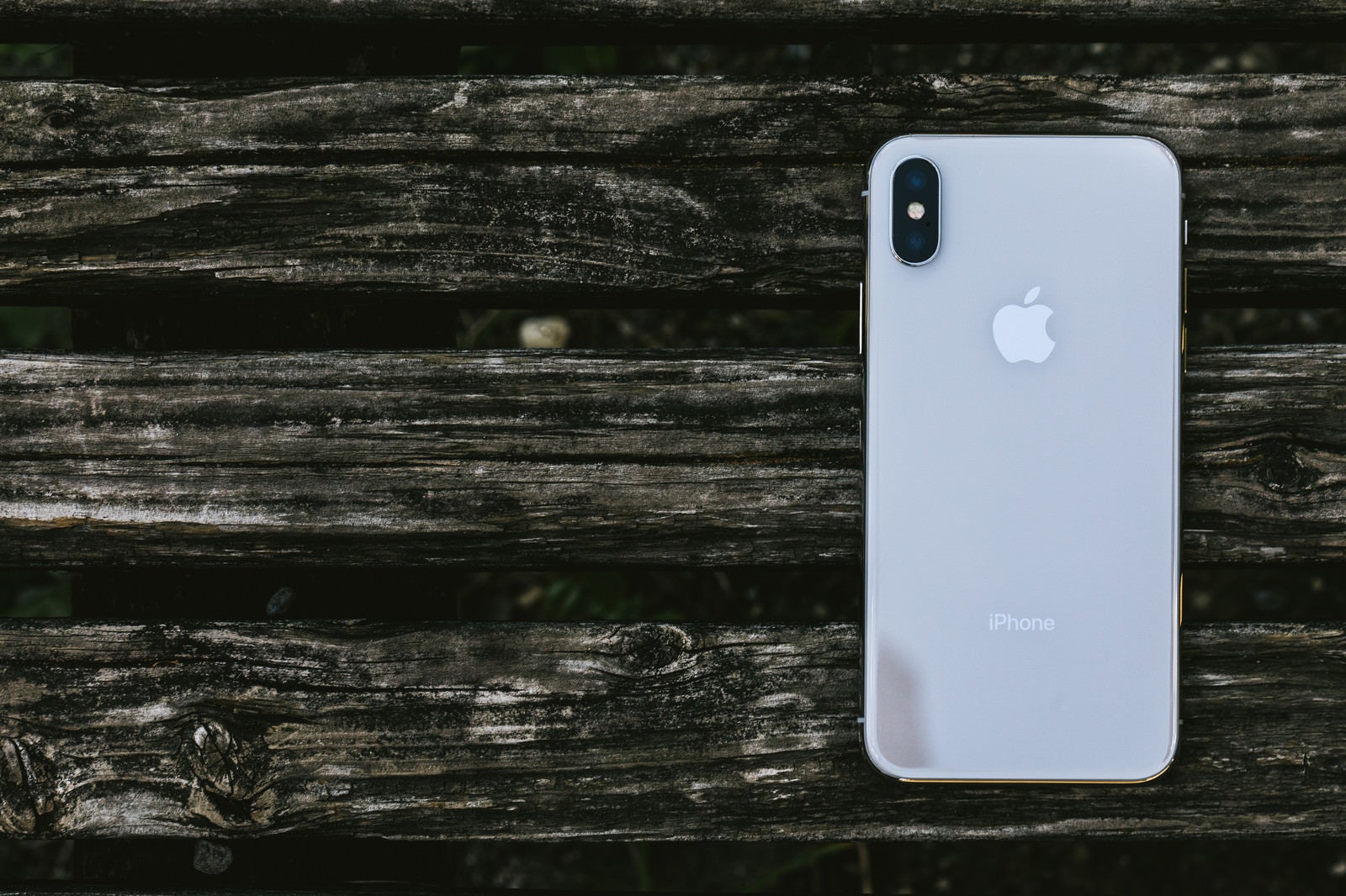 「木の板と iPhone X （背面）」の写真