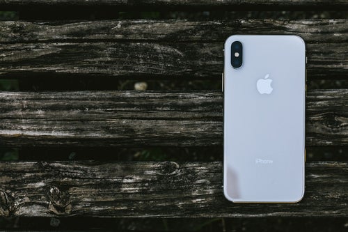 木の板と iPhone X （背面）の写真
