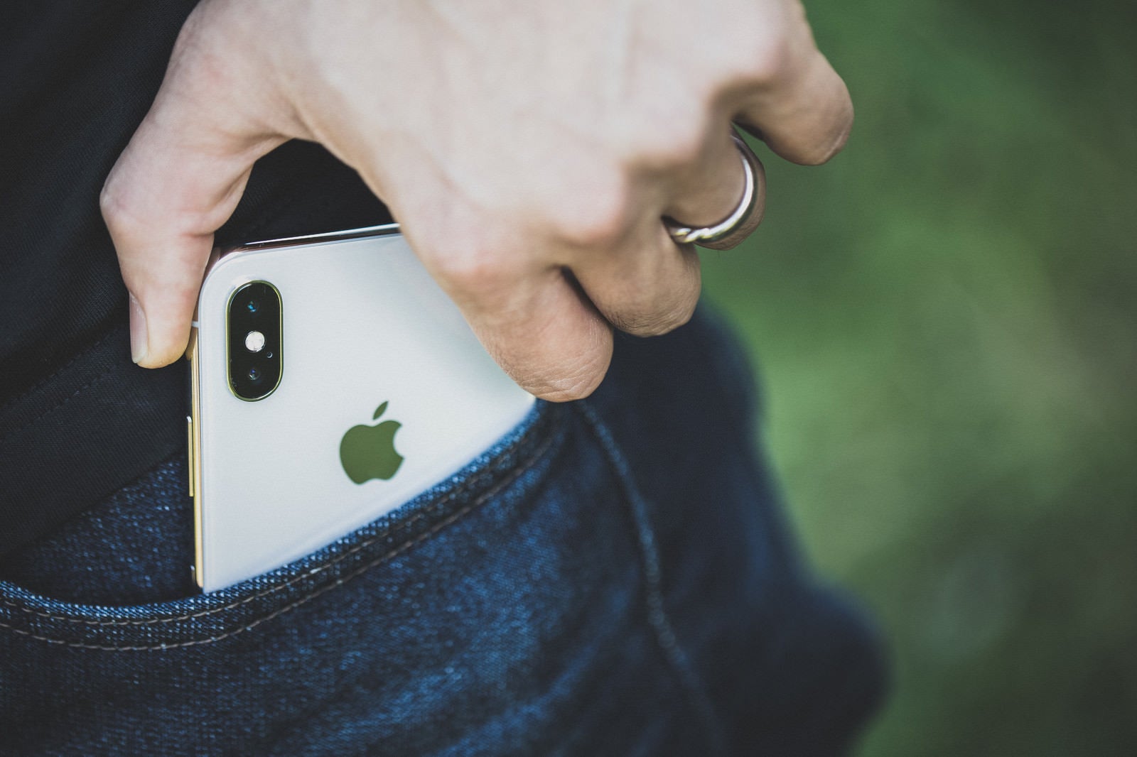 「ポケットから iPhone X を取り出す男性の手」の写真