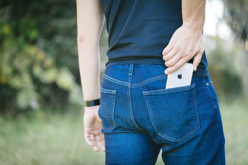 iPhone X を後ろポケットにいれる男性の写真