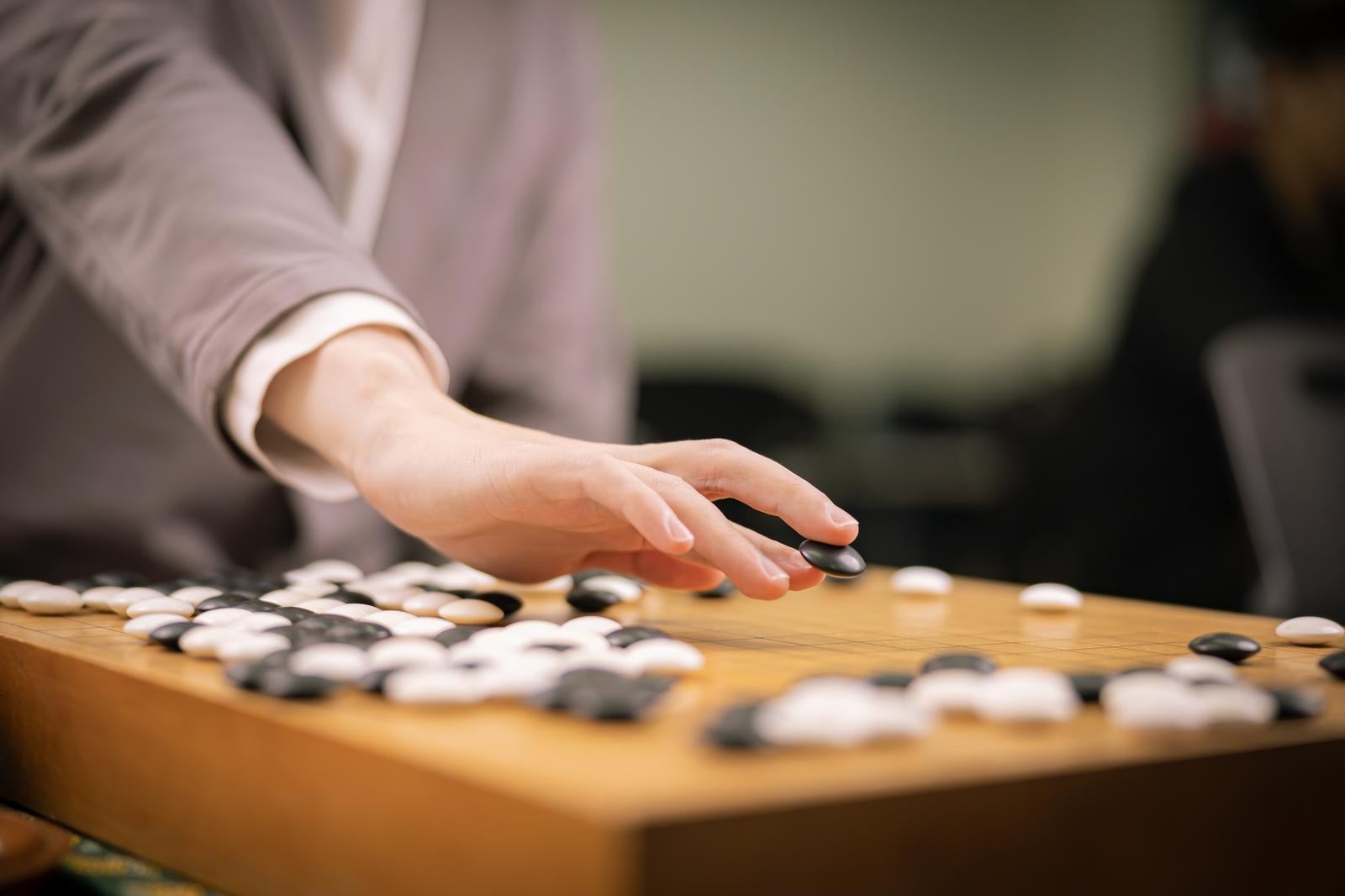 「黒石を打つプロ棋士の手元」の写真