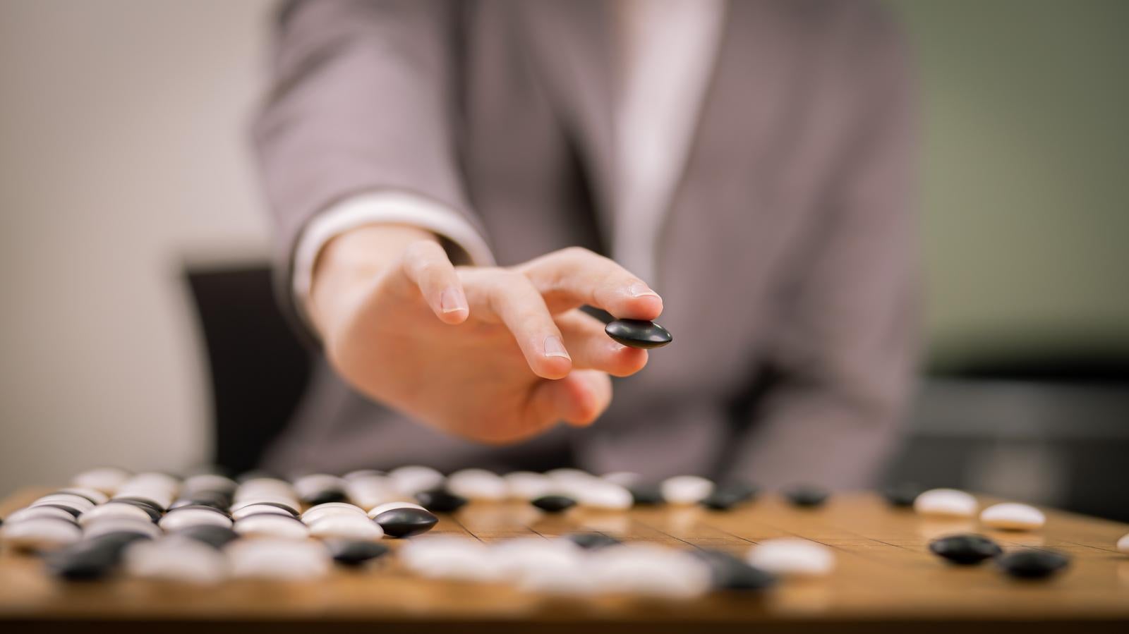 「プロ棋士の黒石を持つ手元」の写真