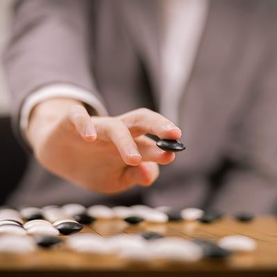 プロ棋士の黒石を持つ手元の写真