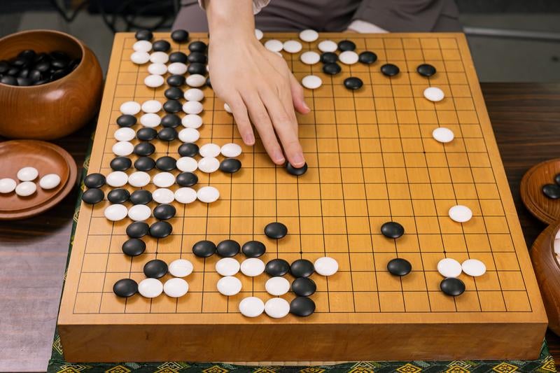 プロ棋士が打つ耳赤の一手と盤面全景の写真