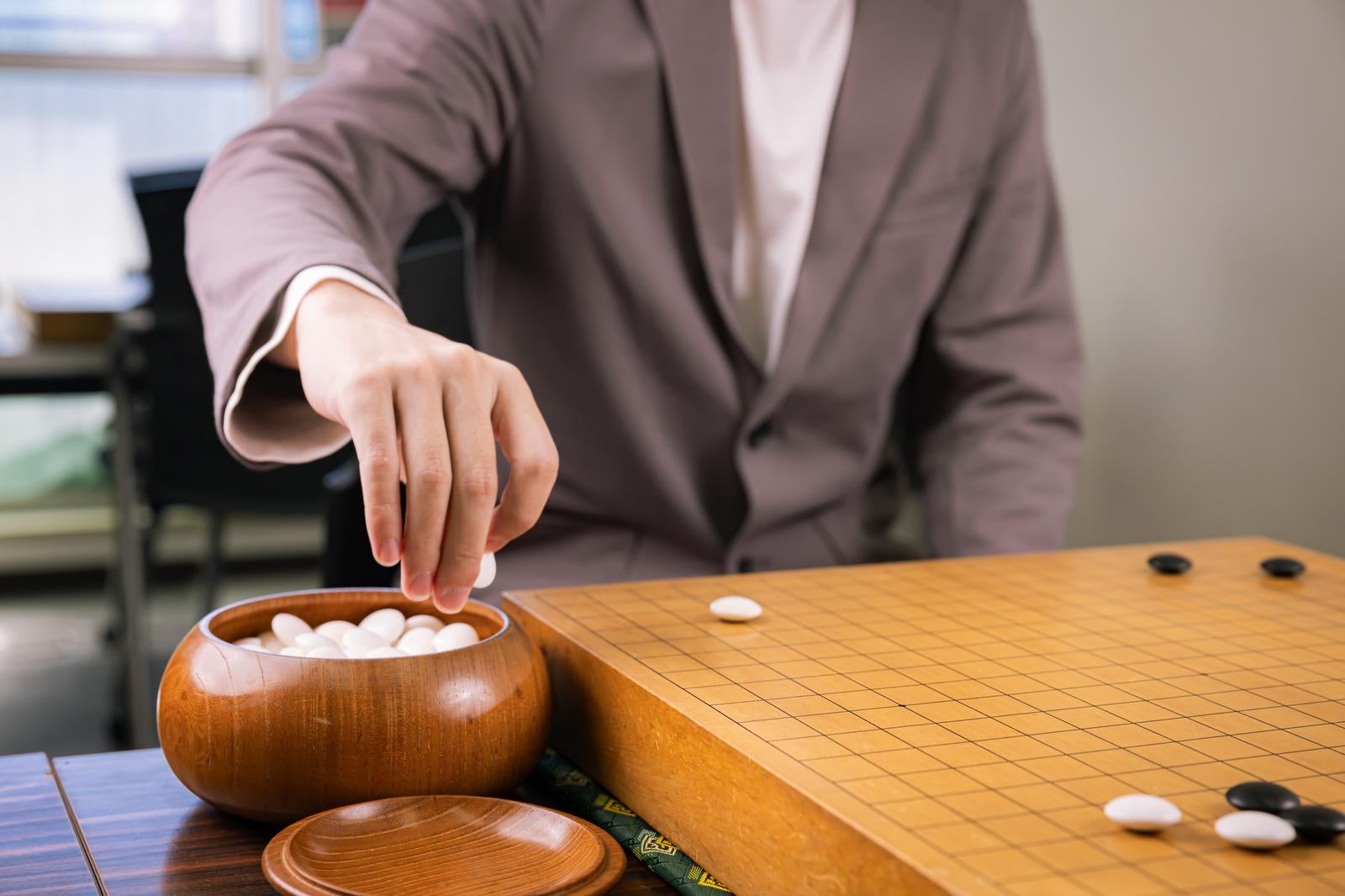 「碁笥から石をつかむプロ棋士の手元」の写真