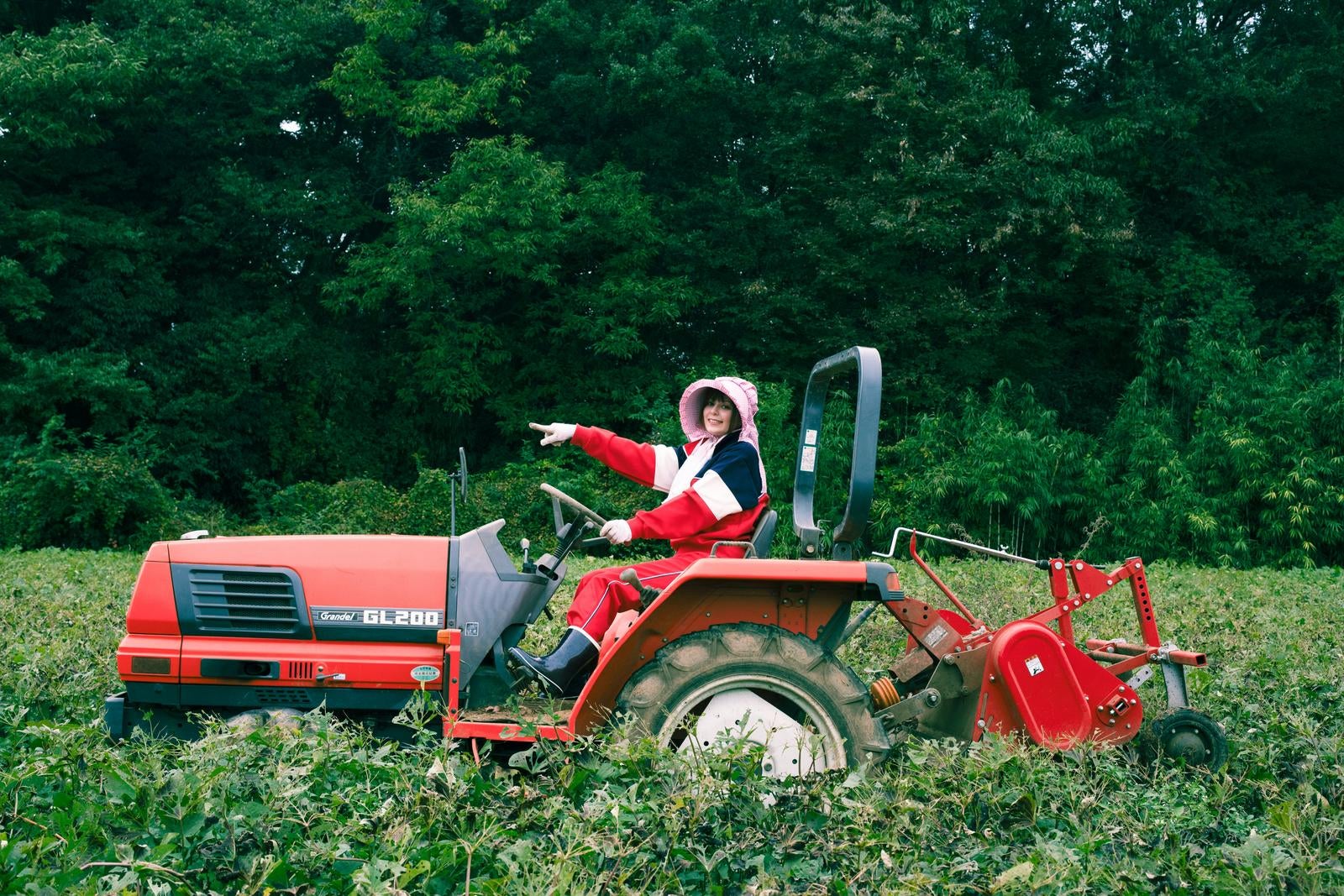 「さつまいもの収穫でトラクターを運転する女性農家」の写真［モデル：ラミエル］