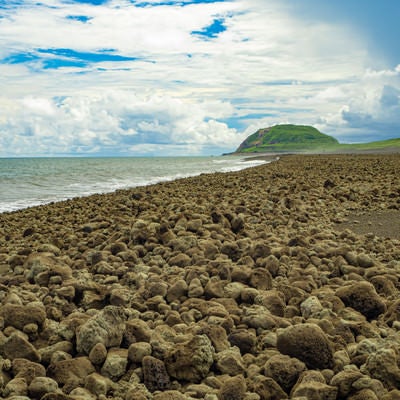 翁浜に漂着した無数の岩塊と摺鉢山の写真