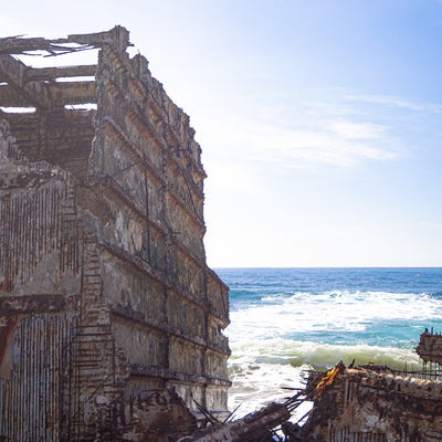 ボロボロになり骨組みの鉄筋が露わになったコンクリート船の残骸の写真