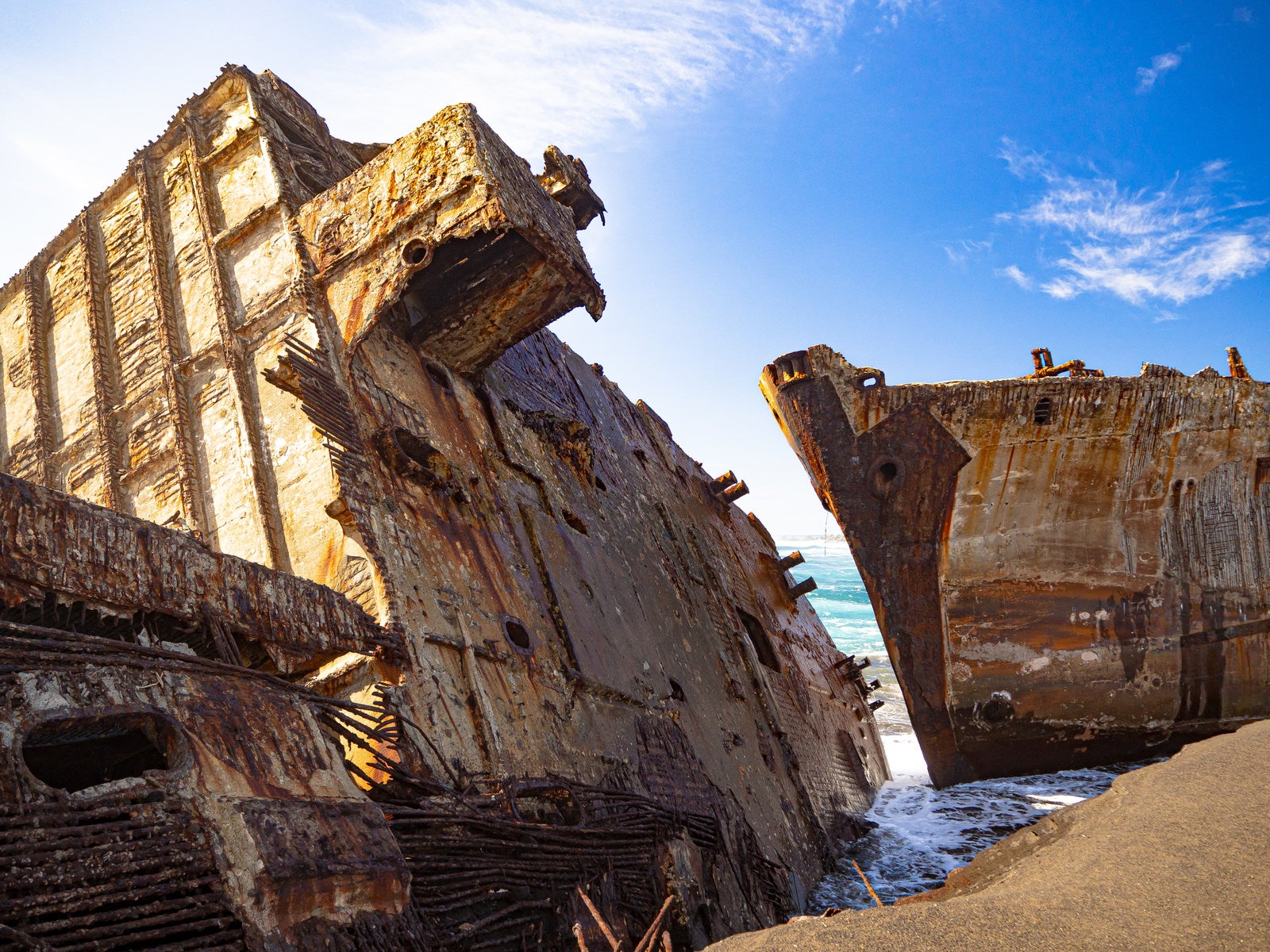 「千鳥ヶ浜の波打ち際に横たわる船の残骸」の写真