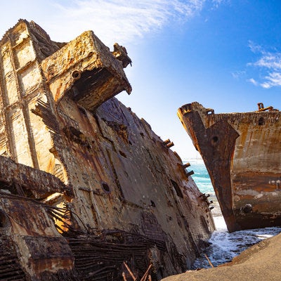 千鳥ヶ浜の波打ち際に横たわる船の残骸の写真