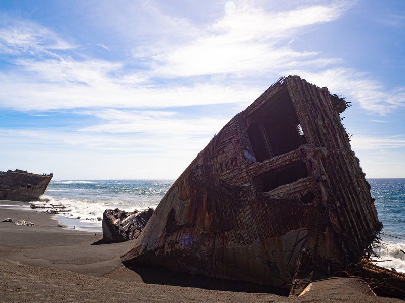 硫黄島千鳥ヶ浜の波打ち際に横たわる船の残骸と続く白波