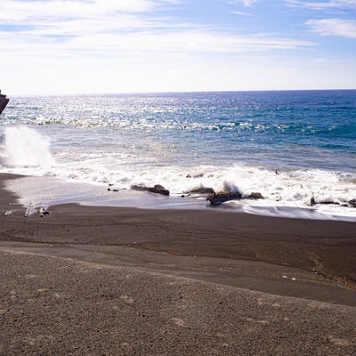 千鳥ヶ浜の波打ち際に散乱する瓦礫にぶつかり砕ける波の写真