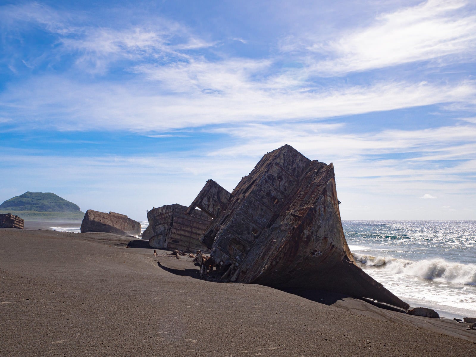 硫黄島の千鳥ヶ浜に横たわるコンクリート船の残骸と摺鉢山