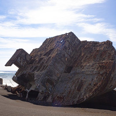 ボロボロに朽ちて千鳥ヶ浜に横たわる海底の隆起によって姿を現した船の残骸の写真
