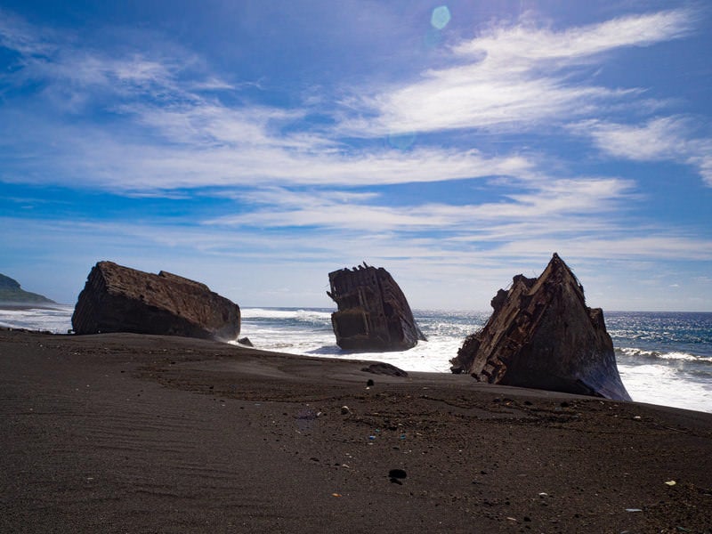 砕け泡立つ白い波に囲まれ横たわる硫黄島・千鳥ヶ浜の沈船群の写真