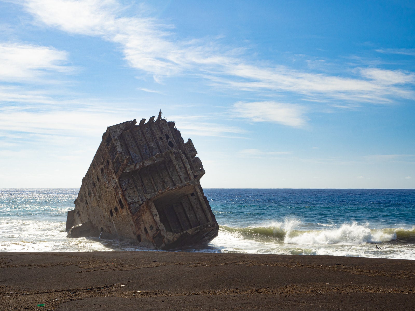 「キラキラと光る波が寄せる硫黄島・千鳥ヶ浜のコンクリート船の残骸」の写真