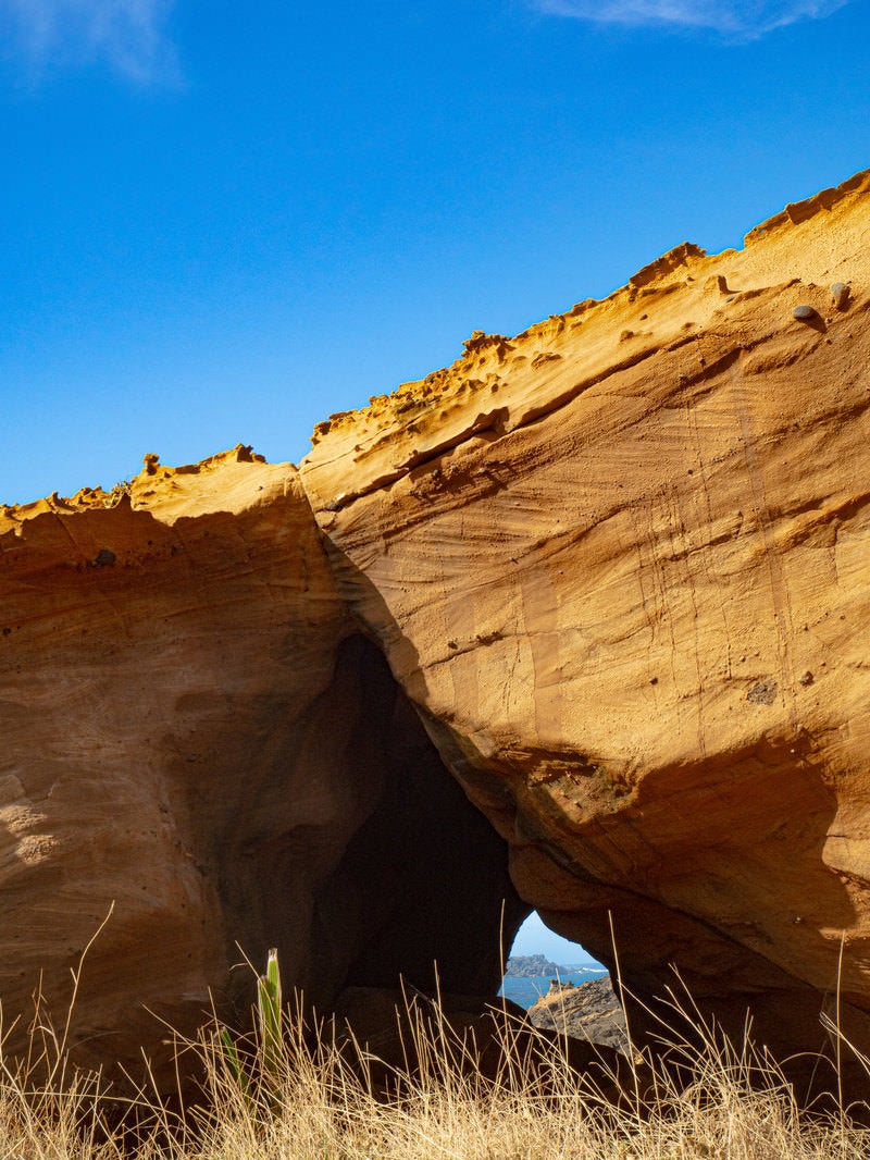 「釜岩に立つ巨大な岩に開いた穴」の写真