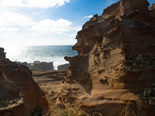 釜岩の奇石の合間から見える輝く海の写真