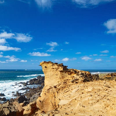 青空と青い海に向かって特徴ある姿でそそり立つ硫黄島の釜岩の奇岩の写真