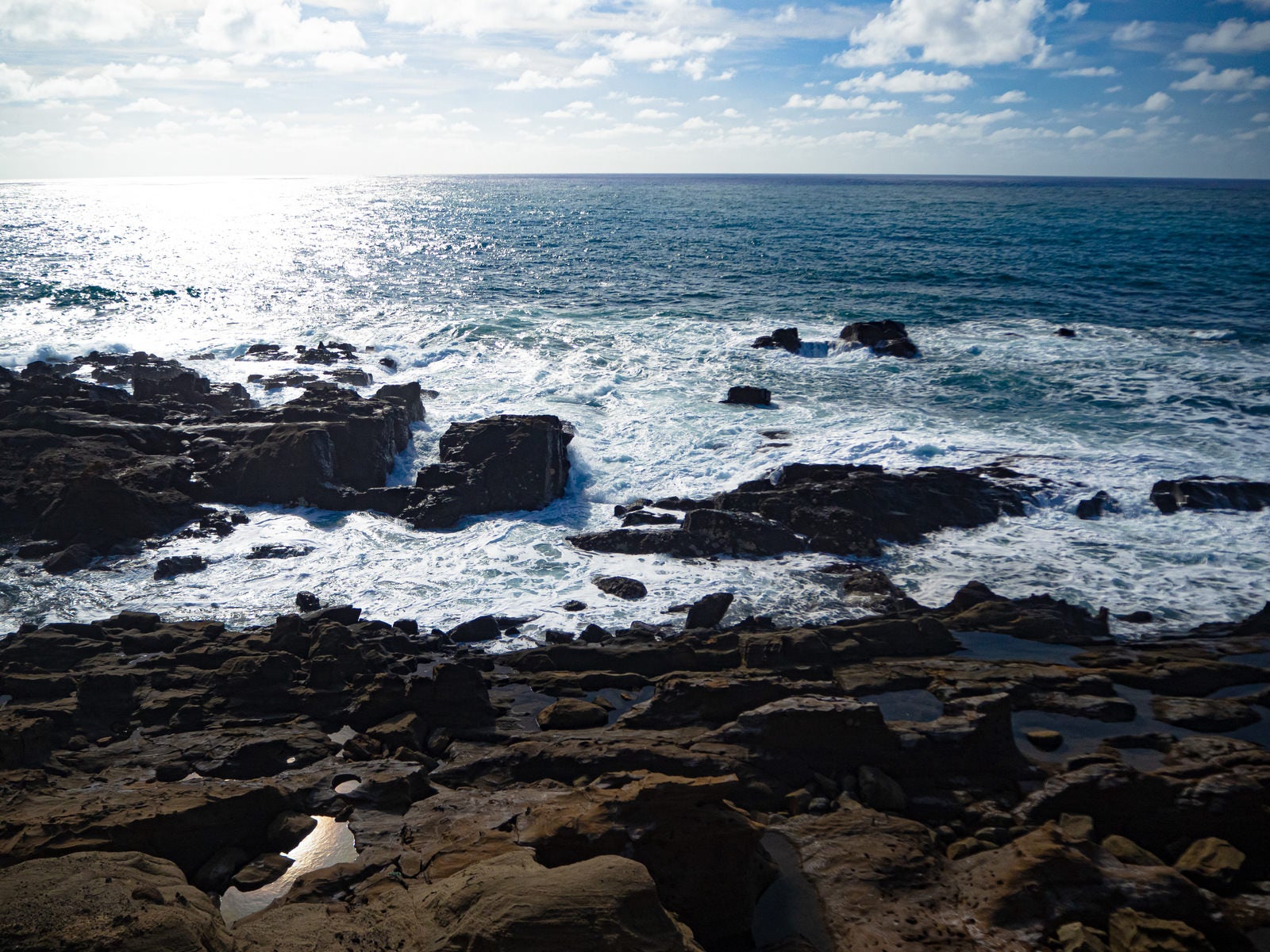 「釜岩に打ち寄せる波と光り輝く海原」の写真