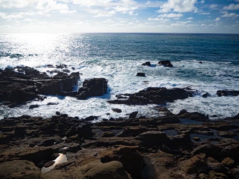 釜岩に打ち寄せる波と光り輝く海原の写真