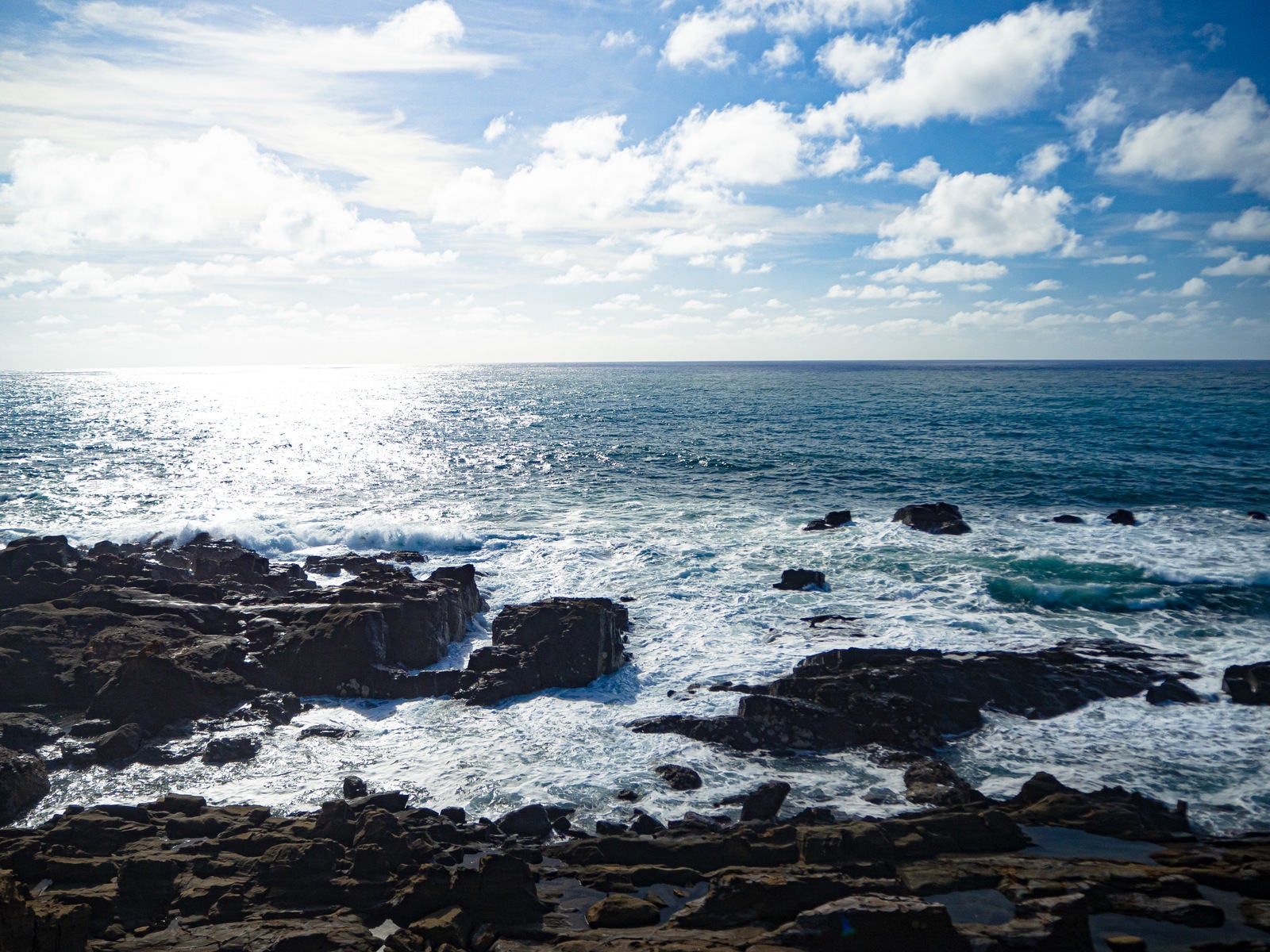 「硫黄島・釜岩から見る光る海と寄せて砕ける波」の写真