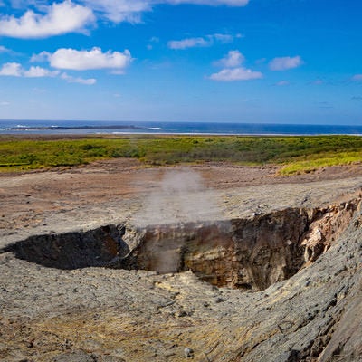 かすかに噴気があがる鶯地獄と沖に見える監獄岩の写真