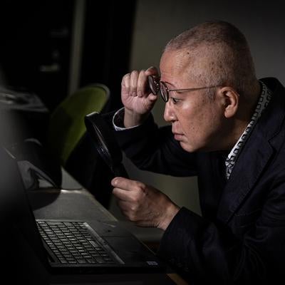 拡大鏡でパソコン画面を二度見する管理職の写真