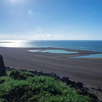輝く海とここ一年の隆起で取り残された為八海岸の水たまりの写真
