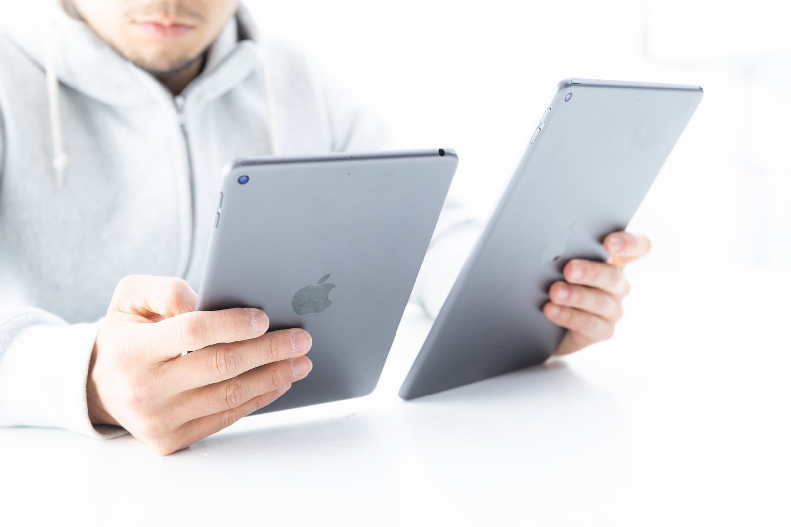 「iPadのディスプレイを細かく見比べる男性」の写真