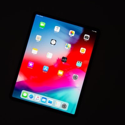 黒い背景に傾けたタブレットのホーム画面（12.9インチ iPad Pro 2018）の写真