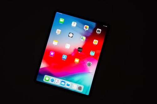 黒い背景に傾けたタブレットのホーム画面（12.9インチ iPad Pro 2018）の写真