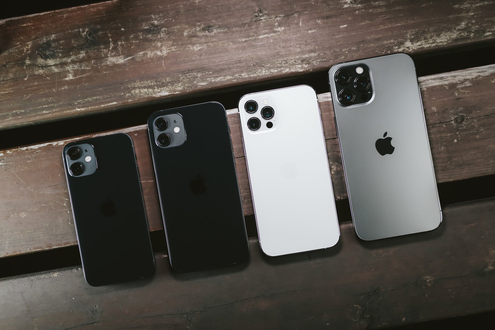 「木目板の上に並べられた iPhone 12 シリーズ」の写真