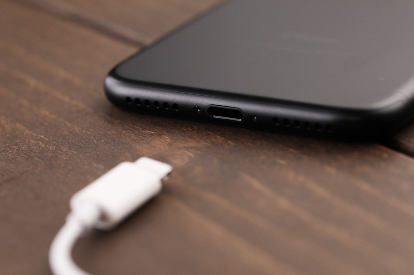 「薄型のスマートフォンと充電コネクタ」の写真