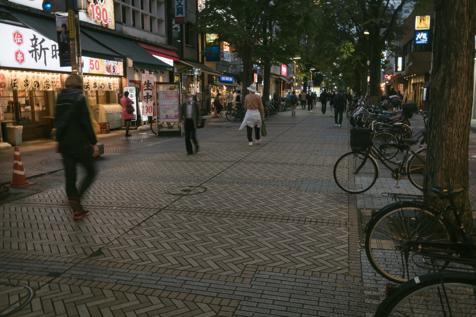 「イセザキモールの歩道に停まる自転車と行き交う人々」の写真