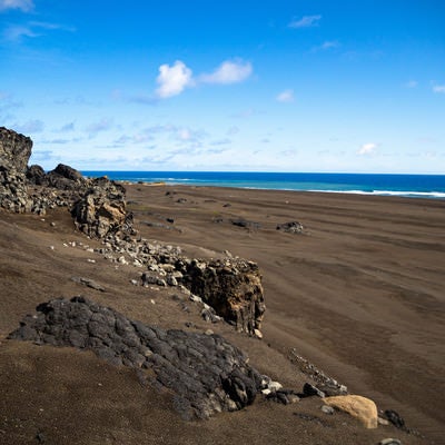 硫黄島の東海岸のゴツゴツした岩と黒い砂浜の写真