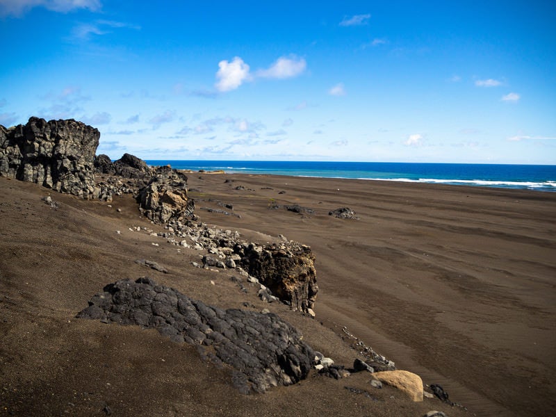 硫黄島の東海岸のゴツゴツした岩と黒い砂浜の写真